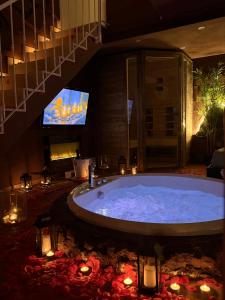a large bathroom with a tub with a tv and candles at Ama Collection Esclusive Spa in Bologna