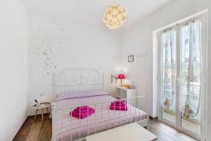 a white bedroom with a pink bed with pink pillows at Il Leone Bianco Affittacamere in Albenga