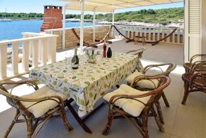 a table with wine bottles and chairs on a balcony at Dalmatino 3 Rukavac Vis in Rukavac