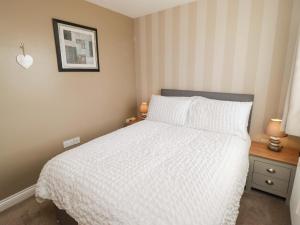 a bedroom with a bed with a white comforter at Twyni Bach in Burry Port