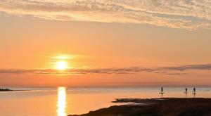 two people standing on the beach watching the sunset at Klintehamn Rooms - Near the Sea in Klintehamn +2 photos