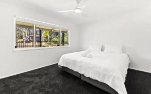a white bedroom with a bed and a window at Poppi's Paradise in Sanctuary Point