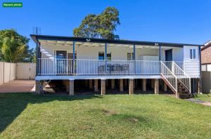 a house with a large deck and a yard at Poppi's Paradise in Sanctuary Point