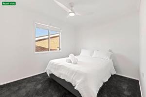 a white bedroom with a bed with a window at Poppi's Paradise in Sanctuary Point