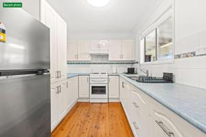 a white kitchen with white appliances and a wooden floor at Poppi's Paradise in Sanctuary Point +6 photos