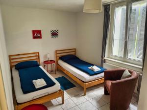 a bedroom with two twin beds and a chair at Casa Carmela in Solothurn