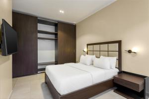 a bedroom with a white bed and a flat screen tv at Metro Apartments in Lagos