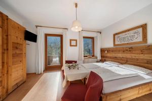 a bedroom with a large bed and a table at Mayrhof Zimmer, Bauernhofurlaub in San Pancrazio dʼUltimo