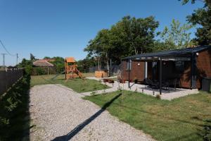 a small shed with a playground in a yard at Tisza-tavi Kiserdő Lodge in Tiszaderzs