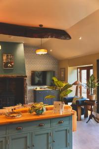 a kitchen with blue cabinets and a living room at Town Gate Cottage in Stainland