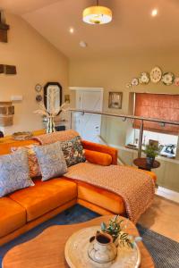 a living room with an orange couch and a table at Town Gate Cottage in Stainland