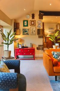 a living room with orange furniture and a red table at Town Gate Cottage in Stainland