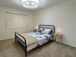 a bedroom with a bed and a chandelier at 3BR Retreat with Sunset Views over Brisbane Water in Green Point