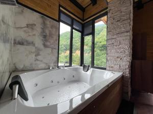 a large white bath tub in a room with windows at Aquarium BUNGALOW UZUNGÖL in Uzungöl