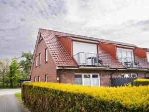 a red brick house with a balcony on a street at Residenz Whg 2 in Norddeich +3 photos