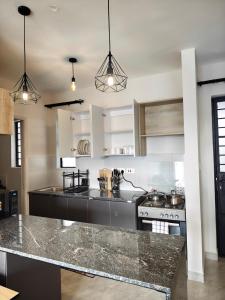 a kitchen with white cabinets and a granite counter top at Chic One Bedroom Apartment near The Kenya School of Government - KSG in Nairobi