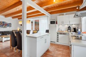 a kitchen with white cabinets and a dining area at Waterkieker in Greetsiel