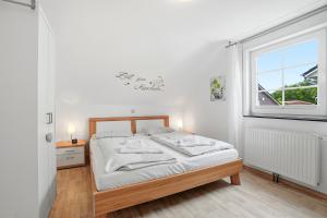 a white bedroom with a bed and a window at Waterkieker in Greetsiel