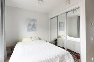 a bedroom with a white bed and a mirror at Moderni avara yksiö Jyväskylän ydinkeskustassa in Jyväskylä