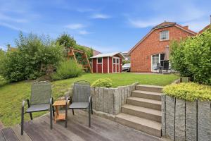 a patio with two chairs and a table and a house at Waterkieker in Greetsiel