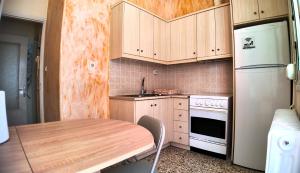 a kitchen with a wooden table and a white refrigerator at Amelie in Loutraki