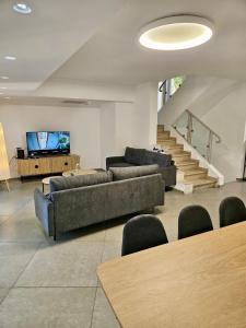 a living room with couches and a flat screen tv at Kosher Villa in earth of Moshava in Jerusalem