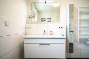 a white bathroom with a sink and a mirror at Möwe - Apartment in der Hafenresidenz mit Balkon & Wellness in Waren +31 photos