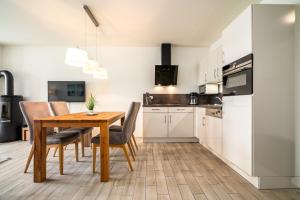 a kitchen and dining room with a wooden table and chairs at Möwe - Apartment in der Hafenresidenz mit Balkon & Wellness in Waren
