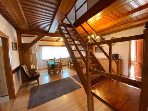 a living room with a wooden staircase and a dining room at Penzion Mühl in Bedřichov