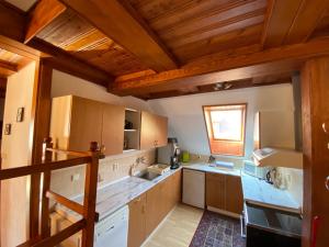 a large kitchen with wooden ceilings and wooden cabinets at Penzion Mühl in Bedřichov