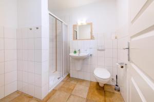 a white bathroom with a toilet and a sink at Haus Sonnenschein 2 in Ahrenshoop +7 photos