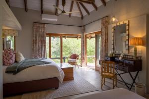 a bedroom with a bed and a desk with a mirror at Shimungwe Lodge, Thornybush Game Reserve in Hoedspruit