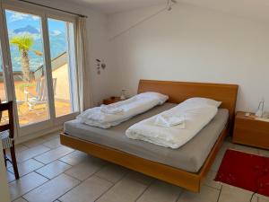 a bedroom with a bed with white sheets and a window at Orizzonte Blu by HolAp SA in Gambarogno