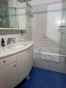 a white bathroom with a sink and a tub at Orizzonte Blu by HolAp SA in Gambarogno +29 photos