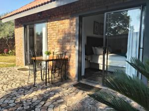 a glass room with a table and chairs and a bed at Nylstroom Guesthouse in Modimolle