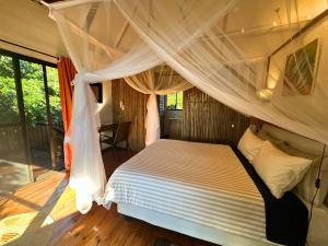 a bedroom with a bed with a mosquito net at Kangela 14 in Ponta Malangane