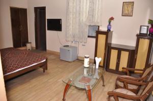 a living room with a bed and a glass table at Hotel Pratiksha in Morādābād