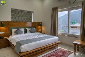a bedroom with a large bed with a large window at Pacific Inn Vistaar Hotels & Resorts in Chamba