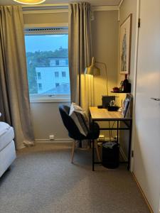 a desk and a chair in a room with a window at Strand Hotel Fevik - by Classic Norway Hotels in Grimstad