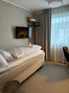 a bedroom with a bed and a tv on the wall at Strand Hotel Fevik - by Classic Norway Hotels in Grimstad