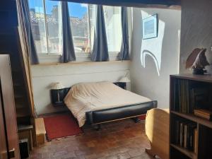 a small bed in a room with windows at Le bateau sur les toits in Cotignac +6 photos