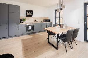 a kitchen with a wooden table and chairs at Küsten Suite Nord - direkte Wasserlage, Terrasse, 70qm in Greetsiel