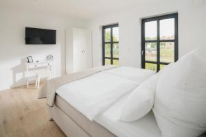 a white bedroom with a bed and a desk at Küsten Suite Nord - direkte Wasserlage, Terrasse, 70qm in Greetsiel