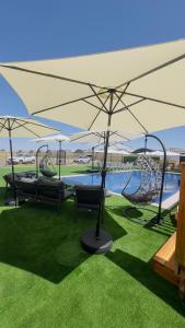 a swing set with umbrellas next to a pool at צימרים שדות אור in Maʼor