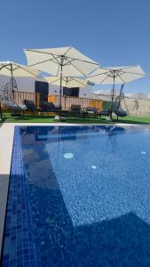 a swimming pool with chairs and umbrellas next to at צימרים שדות אור in Maʼor