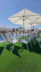 a group of white chairs and a table with umbrellas at צימרים שדות אור in Maʼor +4 photos