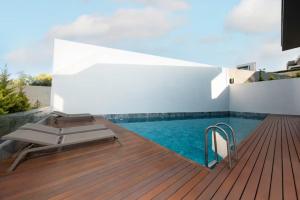 a wooden deck with a pool and a chaise lounge at FOR LARGE FAMILIES, DUPLEX Vılla-304 in Çeşme