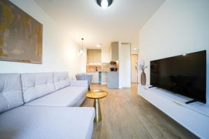 a living room with a white couch and a large flat screen tv at Apartbaltic- Ventus Park 5 in Świnoujście