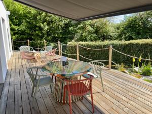 a patio with a glass table and chairs on a wooden deck at Maison des Chênes 64 - Spa Lodge in Boucau