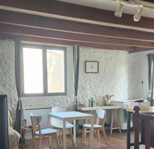 a dining room with tables and chairs and a window at Le logis des vendangeurs in Puisserguier